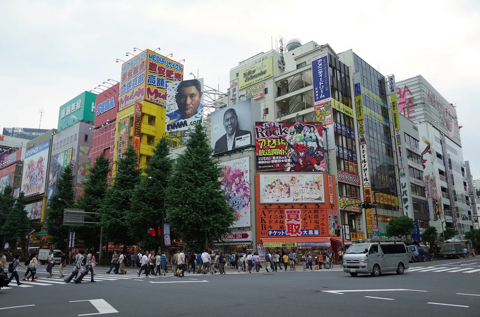 Akihabara crossing with tall billboard-covered buildings and pedestrians