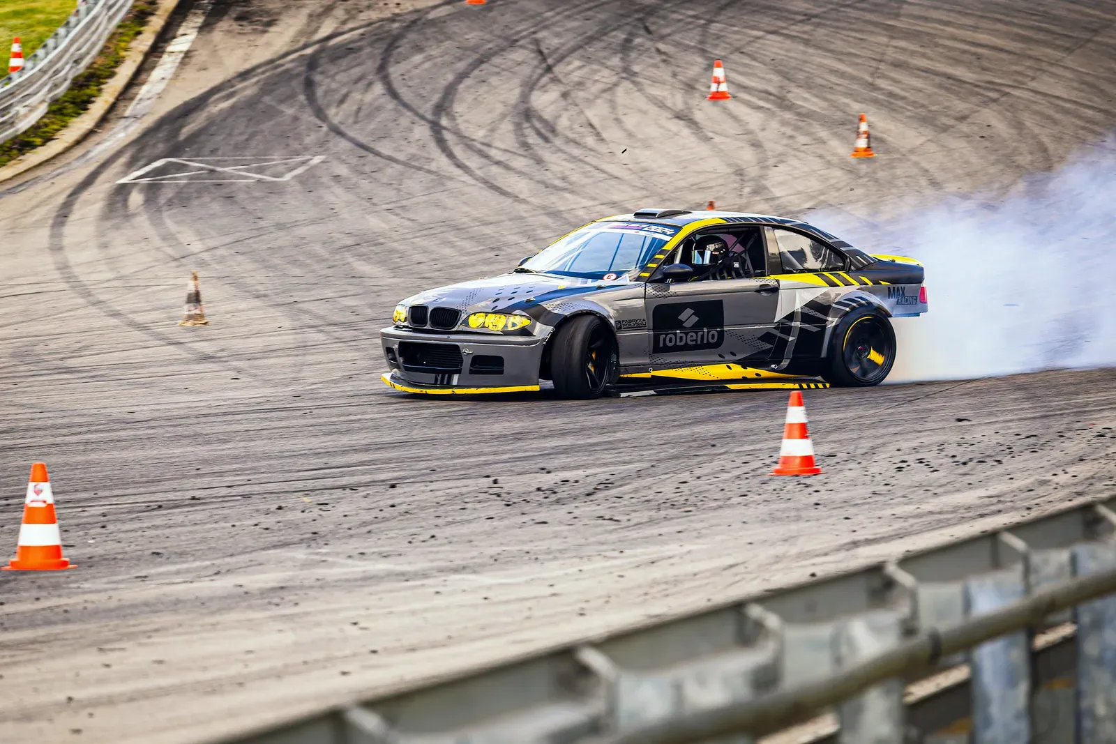 Grey BMW drift car sliding past orange cones on a tyre-marked track