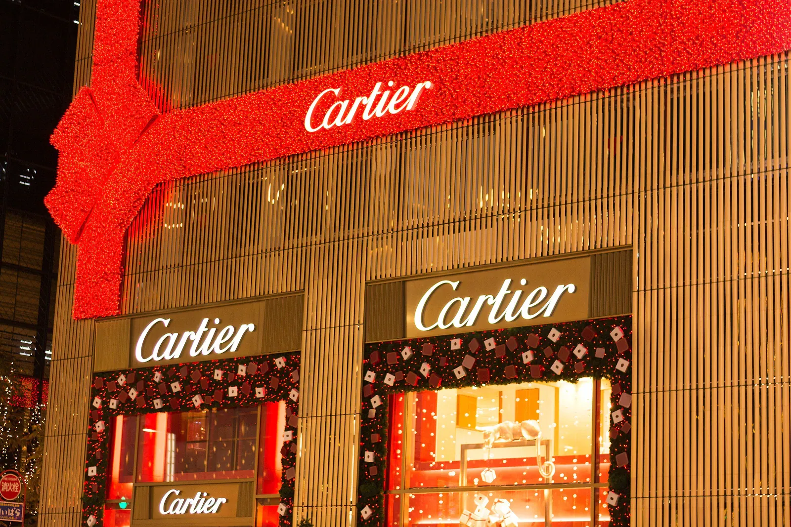 Red and gold Cartier shopfront decorated with a ribbon at night