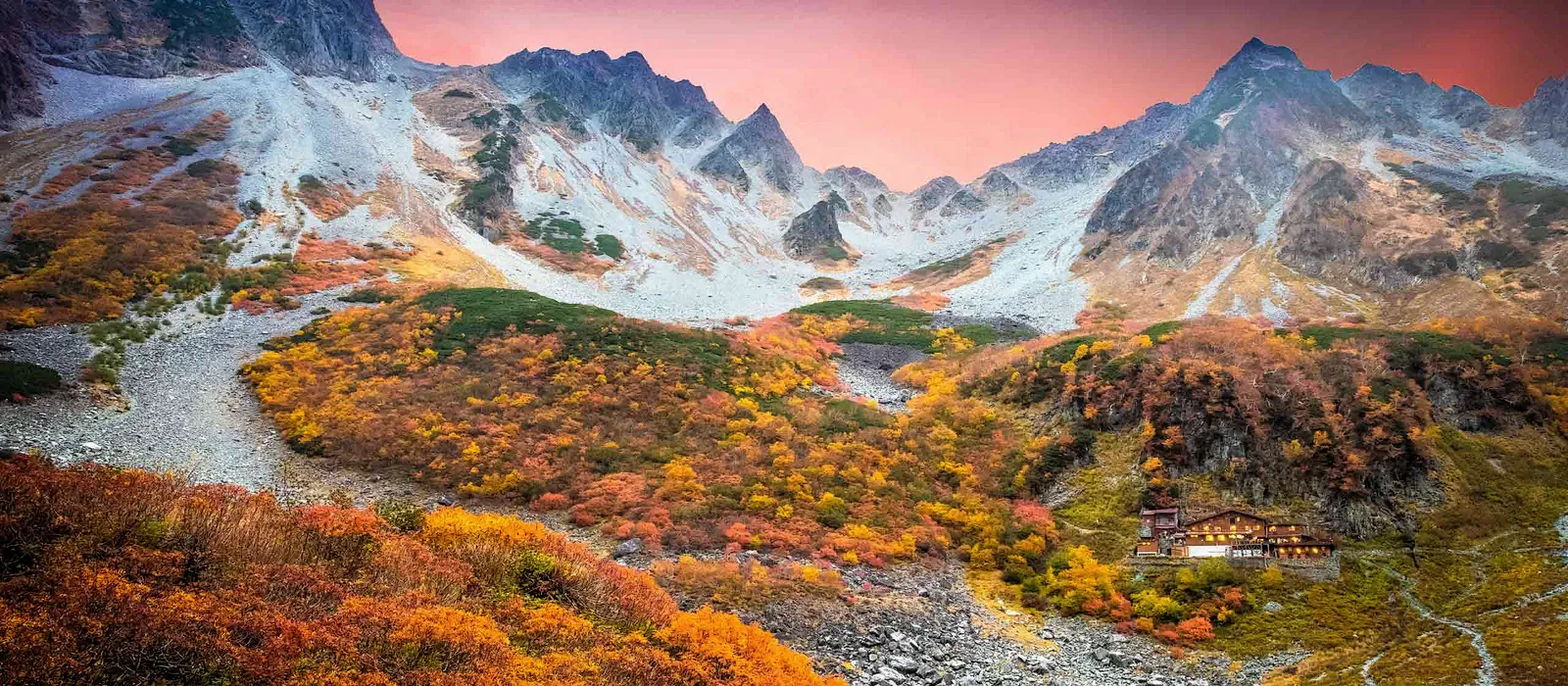 Autumn-coloured alpine valley below jagged peaks in sunrise glow