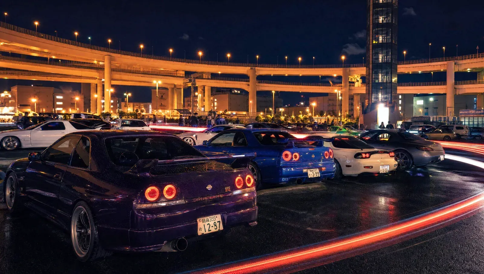 Skylines parked at night beneath the Daikoku interchange loops, tail lights glowing
